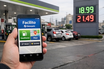 Mano sostiene smartphone con aplicación Facilito de Osinergmin, estación de servicio, surtidores, vehículos y cartel de precios 18.99 y 21.49.