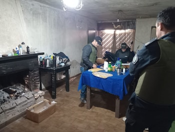 Varias jeringas plásticas, agujas hipodérmicas en sus empaques, una caja de clenbuterol y el borde de una computadora portátil sobre un mantel