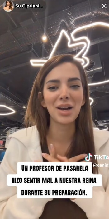 Suheyn Cipriani con cabello castaño claro, vestida de blanco, hablando con expresión concentrada. Una superposición de texto dice: "Un profesor de pasarela hizo sentir mal a nuestra reina durante su preparación"