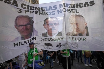 Varios manifestantes llevan una pancarta con imágenes de los premios Nobel argentinos César Milstein, Bernardo Houssay y Luis Federico Leloir en una marcha de protesta para pedir más fondos para las universidades públicas en Buenos Aires en octubre de 2024. La última conferencia de César Milstein en la Universidad de Buenos Aires en 1999 enfatizó la necesidad del apoyo estatal a la ciencia básica (AP)