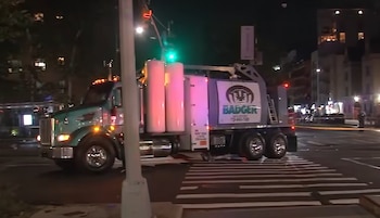 Un camión industrial detenido de noche sobre un paso de peatones junto a una bicicleta caída en la calle