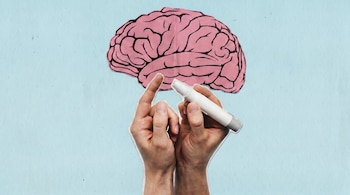 Ilustración de un cerebro rosa con líneas negras sobre un fondo azul claro. Debajo, dos manos sostienen un punzador de glucosa tocando un dedo.