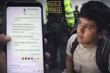Primer plano de una mano sosteniendo un teléfono mostrando un chat de WhatsApp; en segundo plano, un joven y un oficial de policía desenfocados.
