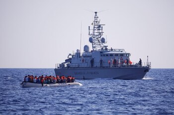 La patrullera italiana Guardia di Finanza llega para embarcar a los inmigrantes, que se encuentran en un bote de goma para llevarlos a Lampedusa, cerca del barco de rescate de la ONG Open Arms Astral, en aguas internacionales al sur de Lampedusa, en el Mar Mediterráneo central, el 13 de agosto de 2024. REUTERS /Juan Medina