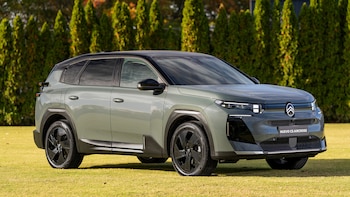SUV Nuevo Citroën C5 Aircross verde grisáceo estacionado sobre césped verde, con una hilera de árboles cipreses al fondo bajo un cielo despejado