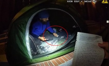 Un hombre con gorro azul dentro de una carpa verde, con un círculo rojo sobre el suelo y una nota manuscrita en primer plano