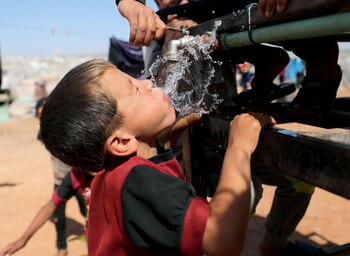 Un niño bebe agua en