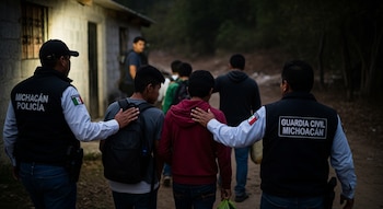 Agentes de la Policía Michoacán y Guardia Civil Michoacán, vistos de espaldas, acompañan a un grupo de adolescentes que caminan por un sendero rural.