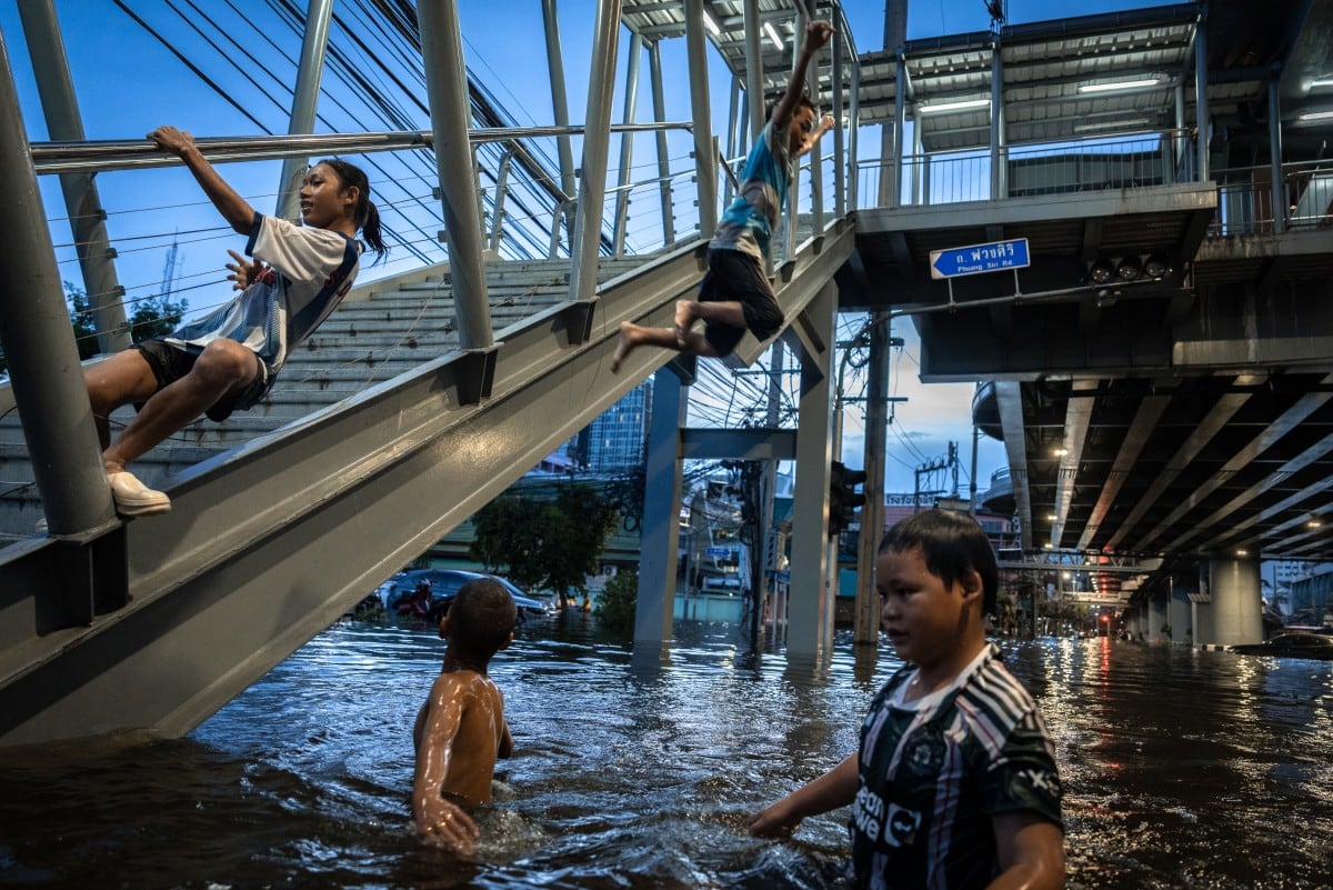 Niños juegan en el agua de la inundación en Bang Kapi, Bangkok. Un restaurante del este de la ciudad no espera reabrir hasta el jueves, tras la limpieza (Chanakarn Laosarakham/AFP)