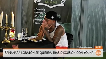 Un hombre con gorra negra y camiseta blanca se cubre el rostro con las manos sentado ante una mesa con velas y comida
