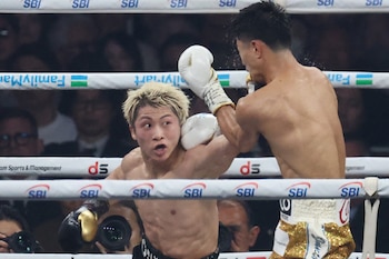 Dos boxeadores en el ring. Un púgil con cabello rubio y guantes blancos recibe un golpe en el lateral de la cabeza de su oponente
