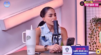 Onelia Molina hablando en un micrófono profesional dentro de un estudio con iluminación rosada, usando una blusa de jean sin mangas