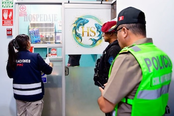 Una funcionaria de Migraciones y dos agentes de la policía peruana frente al mostrador de la recepción de un hospedaje