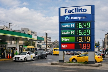 Un grifo limeño con un gran cartel digital azul que muestra precios de combustibles. Taxis y automóviles se ven en la avenida frente a la estación de servicio.