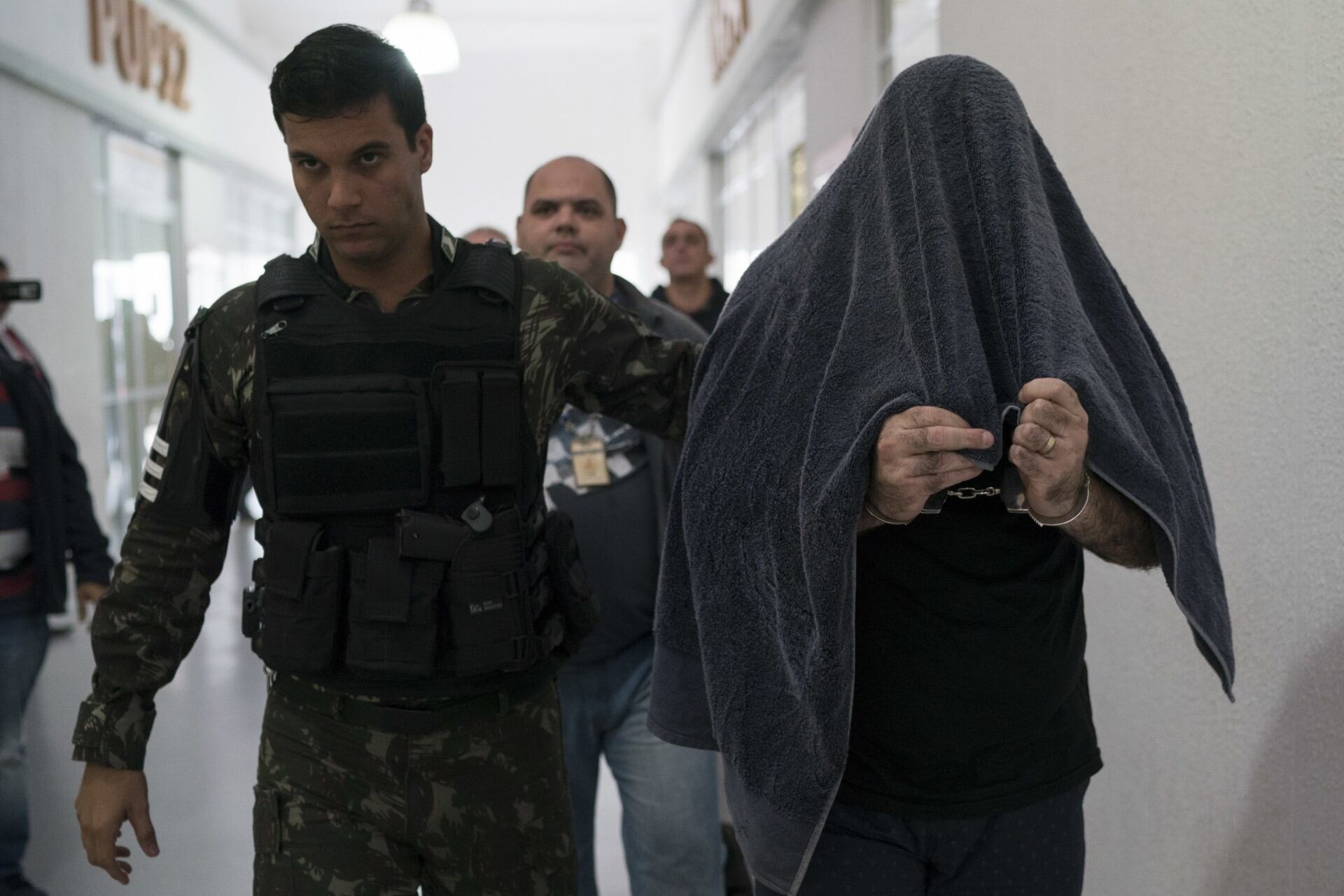 Esta foto del 2 de agosto del 2018 muestra al subteniente del ejército Marco Antonio Gomes Sacramento, derecha, siendo escoltado esposado por un soldado tras ser arrestado por la policía por presuntamente colabora con un grupo paramilitar, conocido como una milicia, en Río de Janeiro, Brasil (AP Foto/Leo Correa)