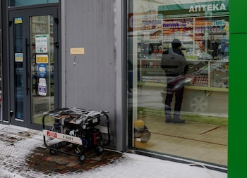 Un residente compra medicamentos en una farmacia que funciona con un generador eléctrico, durante un corte de luz tras un ataque ruso con misiles y drones contra infraestructura civil, en la localidad de Borodianka, región de Kiev, Ucrania, el 15 de diciembre de 2022 (REUTERS/Valentyn Ogirenko)