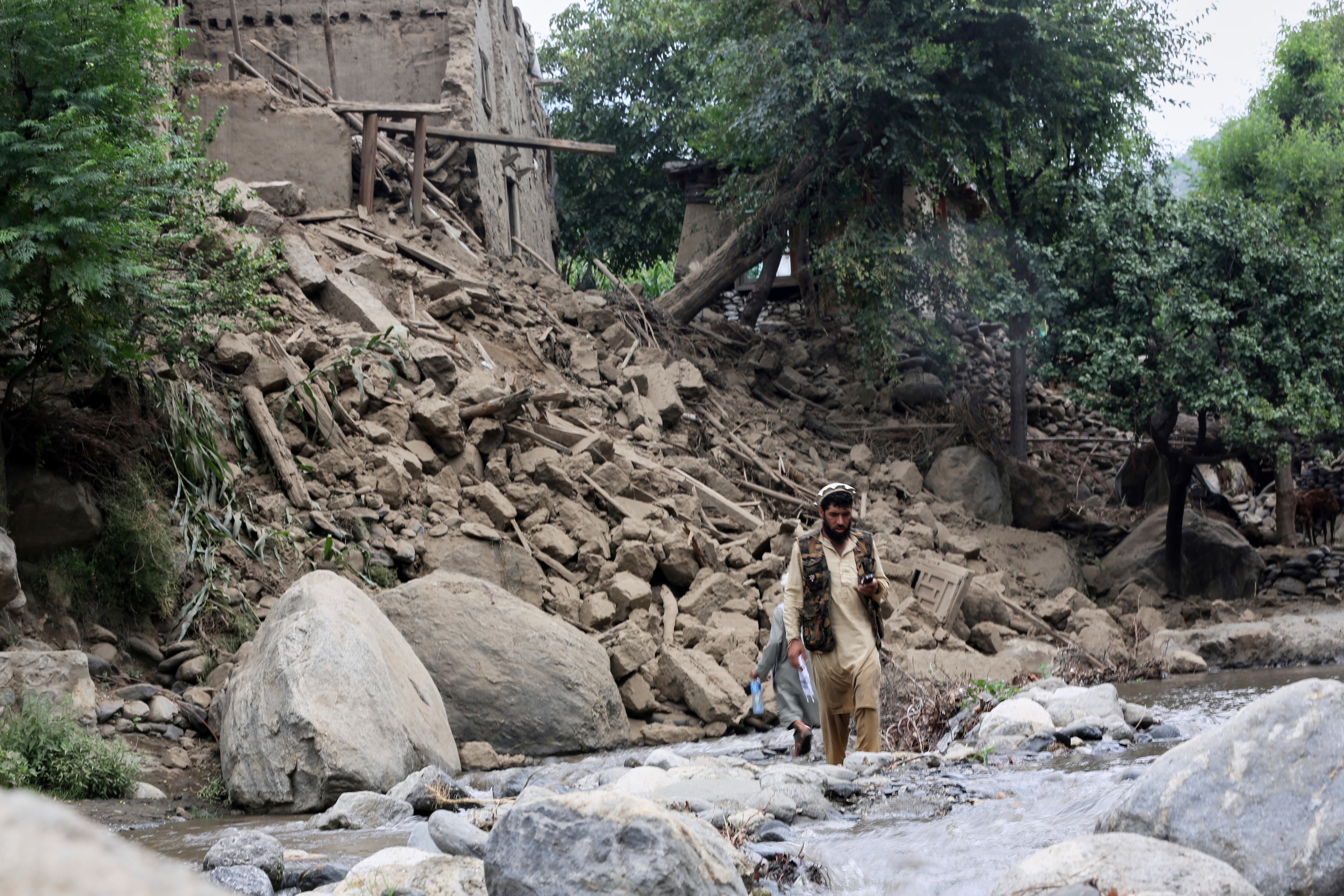 Un hombre y un niño cruzan un arroyo junto a una casa destruida por un terremoto que mató a muchas personas y destruyó aldeas en el este de Afganistán, en Mazar Dara, provincia de Kunar, Afganistán, el lunes 1 de septiembre de 2025. (Foto AP/Wahidullah Kakar)