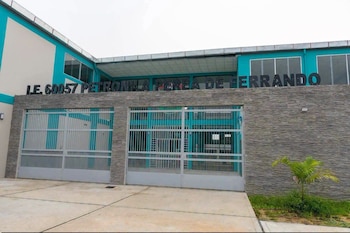 Fachada de un edificio con portón gris, paredes turquesas y letras que dicen I.E. 60057 PETRONILA PEREA DE FERRANDO
