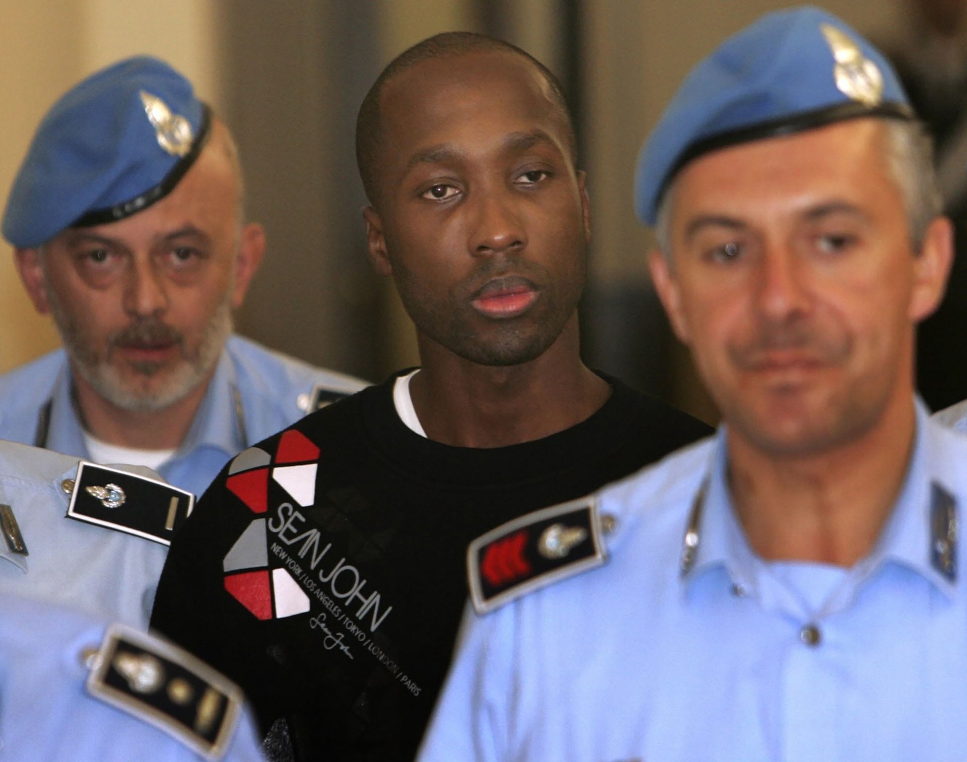 ARCHIVO - Esta fotografía de archivo del viernes 26 de septiembre de 2008 muestra a Rudy Hermann Guede, originario de Costa de Marfil (en el centro), escoltado por agentes de la policía penitenciaria italiana al salir del tribunal de Perugia tras una audiencia (Foto AP/Pier Paolo Cito)