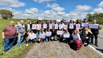 Un grupo de personas sostiene carteles que forman el mensaje Autovía Ya al costado de una carretera