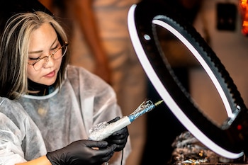 Una especialista en tatuajes de cuero cabelludo realiza una demostración durante un concurso de tatuajes y maquillaje permanente en Naha, prefectura de Okinawa
