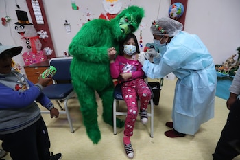 Funcionarios de salud del hospital municipal de La Portada posan junto al "Grinch" mientras vacunan este viernes, a menores entre 5 y 11 años dentro de la campaña navideña de vacunación en La Paz (Bolivia). EFE/Martin Alipaz