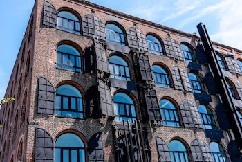 Un edificio industrial reciclado conserva su estructura original mientras incorpora nuevos usos residenciales y comerciales, integrando historia y modernidad.