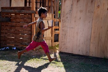 Un niño, desplazado por las crecidas del Río Paraguay, corre con un recipiente lleno de agua en una mano, en su refugio temporal en Asunción, Paraguay, el 18 de marzo de 2023. (AP Foto/Jorge Saenz)