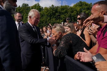 Una mujer besa la mano de Carlos (Yui Mok/Pool via REUTERS)