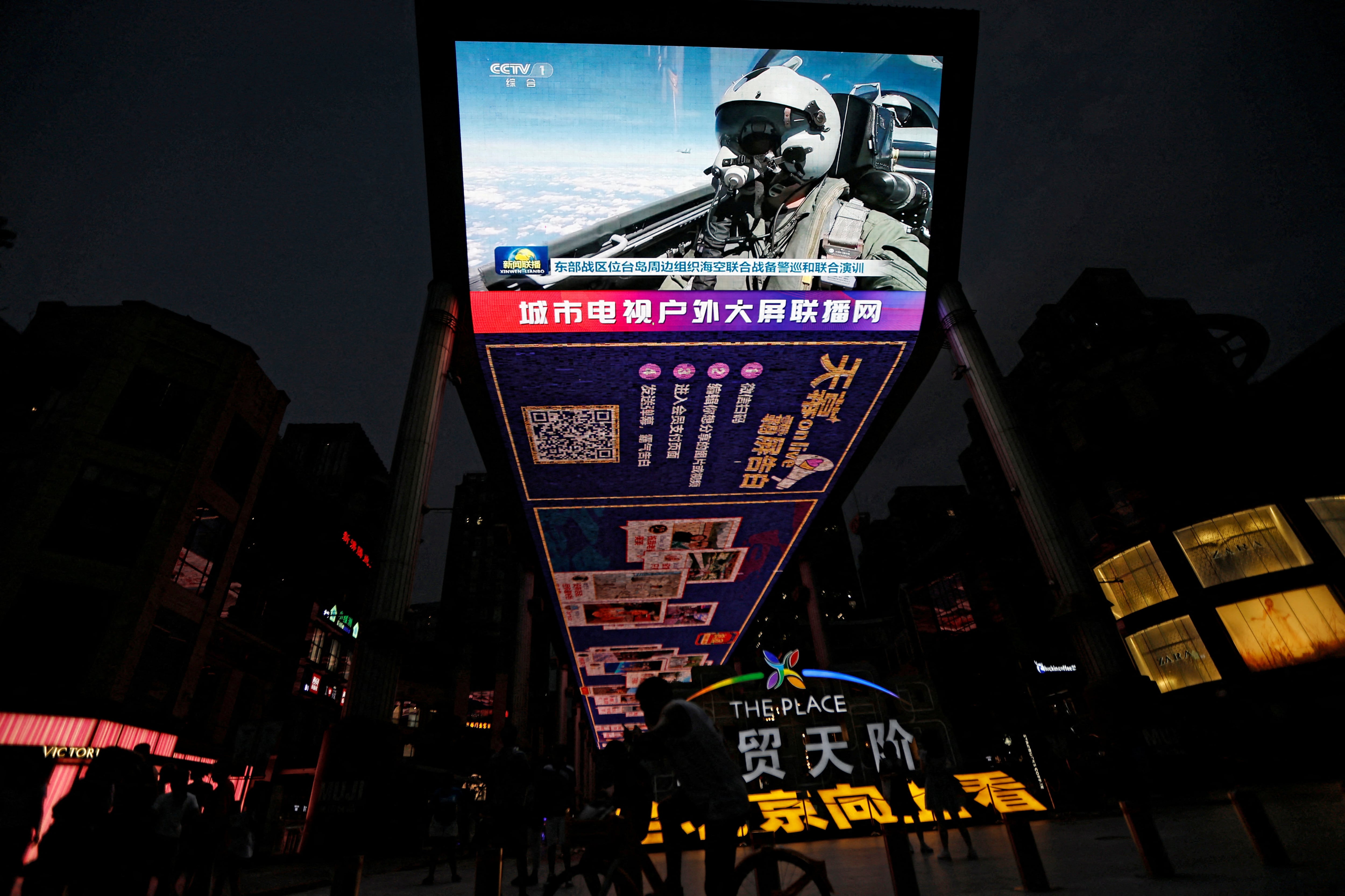 Una pantalla transmite imágenes de noticias de una aeronave de la Fuerza Aérea participando en ejercicios militares del Comando del Teatro Oriental del Ejército Popular de Liberación (EPL) de China alrededor de Taiwán, en una zona comercial de Pekín, China, el 19 de agosto de 2023 (Reuters)