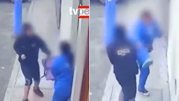 Dos personas borrosas forcejean en una calle. Una lleva una mochila. Una pared blanca y una superficie de calle son visibles