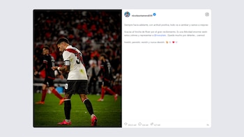 Un jugador de fútbol, Nicolás Otamendi, con camiseta de River Plate, pantalones negros y botines rosas en un campo de juego. De fondo, un estadio con público. Al lado, una publicación de Instagram