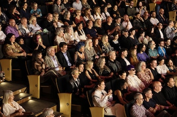 Vista aérea de una gran audiencia sentada en las butacas de un auditorio. Hombres y mujeres de distintas edades observan hacia adelante