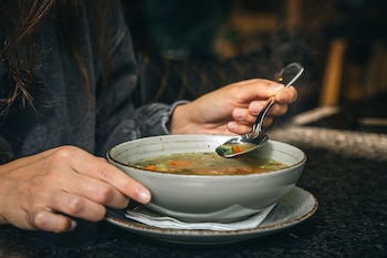 Una mujer tomando una sopa (Magnific)