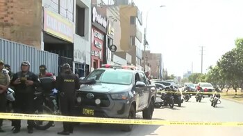 Varios agentes de policía y un vehículo policial permanecen junto a una cinta amarilla de seguridad en una calle con comercios