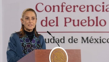 Claudia Sheinbaum habla frente a dos micrófonos en un estrado de madera con el escudo de México, ante un letrero de Conferencia del Pueblo