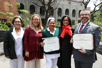 Vista lateral de varias personas sentadas en butacas rojas, aplaudiendo. En primer plano, dos mujeres con cofias de enfermera; una viste de blanco, otra de verde
