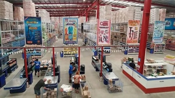 Vista desde arriba del interior de un supermercado mayorista con estantes repletos de productos, pasillos amplios y varias cajas atendiendo a clientes