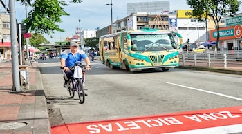 Vista de una autopista de varios carriles con autos, motocicletas, taxis amarillos y carriles marcados para autobuses