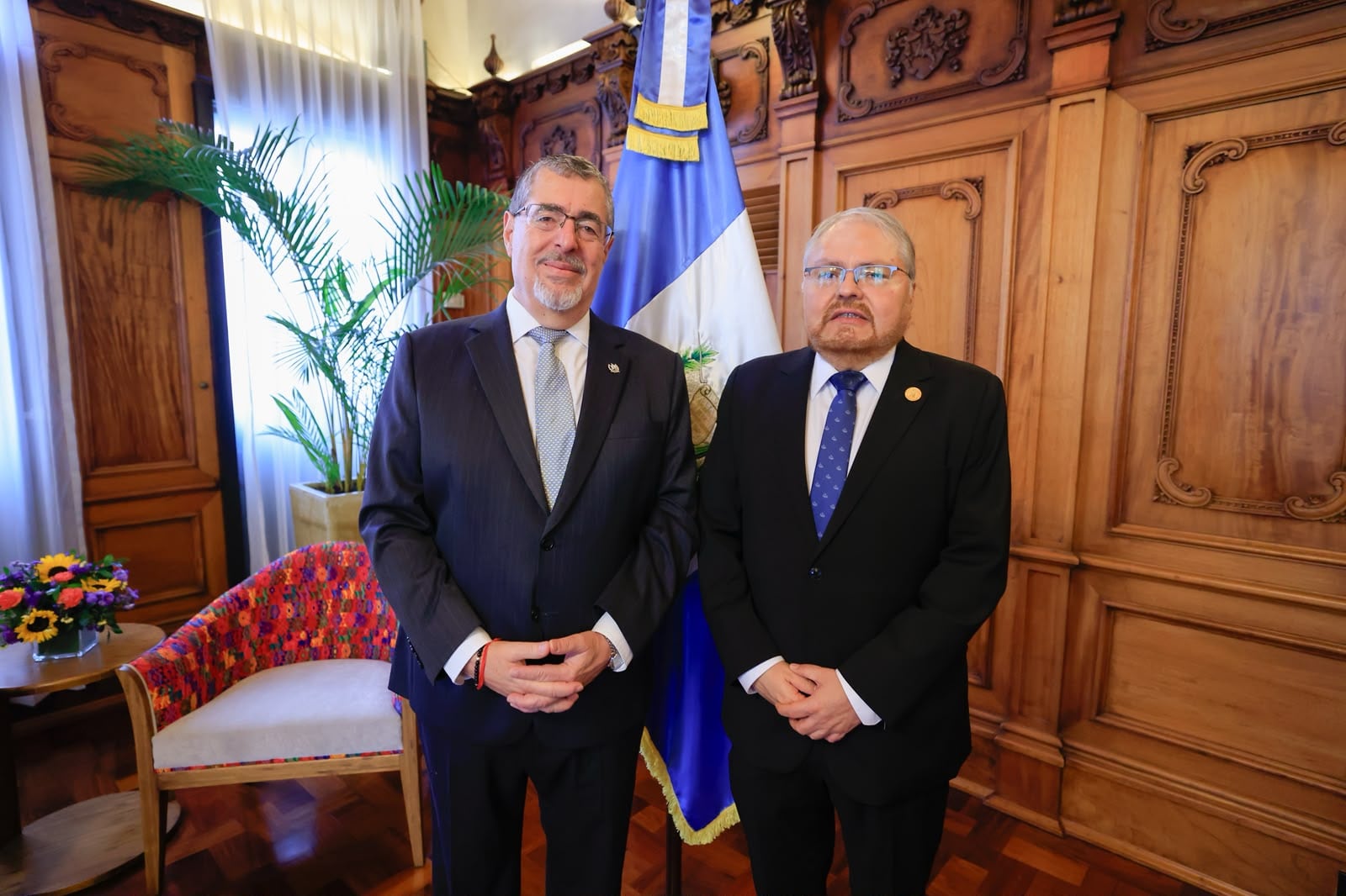 El presidente Bernardo Arévalo saluda a un representante durante un encuentro oficial frente a la bandera de Guatemala. (Secretaría de Comunicación Social de la Presidencia de Guatemala)