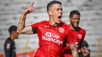 Un jugador de fútbol con camiseta roja del equipo Sport Huancayo levanta el dedo índice y grita en la cancha.