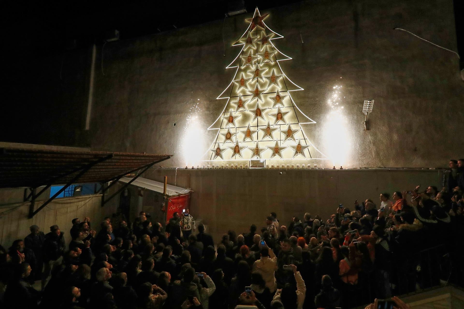 Gente asiste al encendido del árbol de navidad en la iglesia ortodoxa griega de Mar Elias, meses después de que el lugar sufriera un ataque suicida mortal, en el vecindario de Dweila en Damasco, Siria, el martes 23 de diciembre de 2025.(AP Foto/Omar Sanadiki)