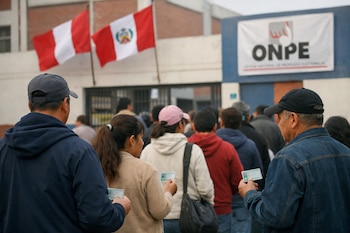 Fila de personas esperando para votar, sosteniendo documentos de identidad. Se ven banderas de Perú y un letrero de la ONPE en el edificio de fondo.