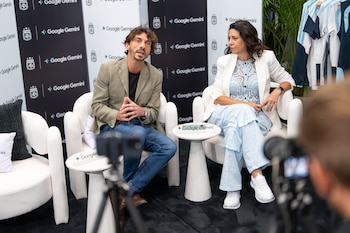 Florencia Sabatini y Ramiro Sánchez sentados en sillas blancas frente a un fondo repetitivo con logos de AFA y Google Gemini en un evento de prensa