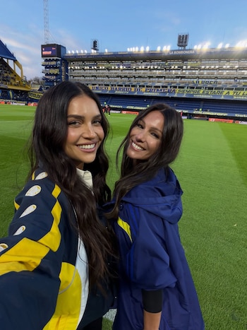 Pampita y Zaira Nara sonríen a la cámara desde el campo de juego de La Bombonera, con las gradas azules y amarillas del estadio de fondo