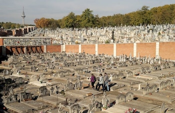 Personas pasan junto a las lápidas de un cementerio durante el día de Todos los Santos en Madrid, España. (REUTERS/Javier Barbancho)