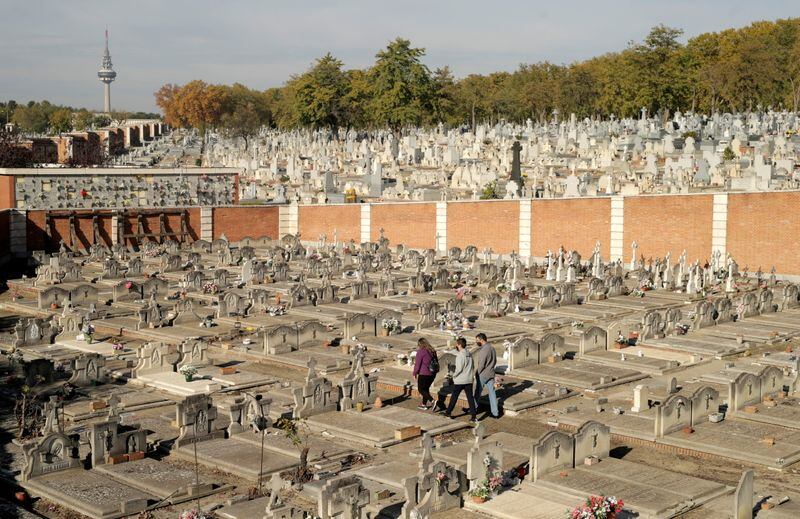Personas pasan junto a las lápidas de un cementerio durante el día de Todos los Santos en Madrid, España. (REUTERS/Javier Barbancho)