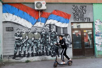 Un niño de etnia serbia circula en su patinete frente a un mural con los colores de la bandera de Serbia en Mitrovica Norte, Kosovo, el 23 de abril de 2023. REUTERS/Valdrin Xhemaj