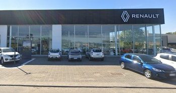Fachada de un concesionario con el letrero de Renault y varios automóviles estacionados en el playón frontal