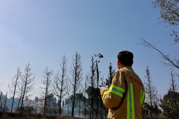Un bombero observa un helicóptero
